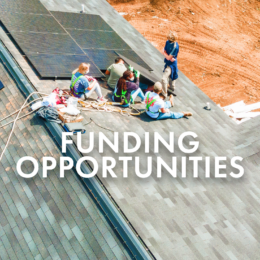 Five undergraduate students sit on top of a shingled roof next to solar panels. Security ropes are tied to their waists and hanging off the roof line. Image is a button that links to Funding Opportunities page.