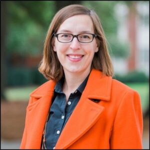 Photo of Kathryn Kloepper, woman with short brown hair and glasses wearing an orange coat